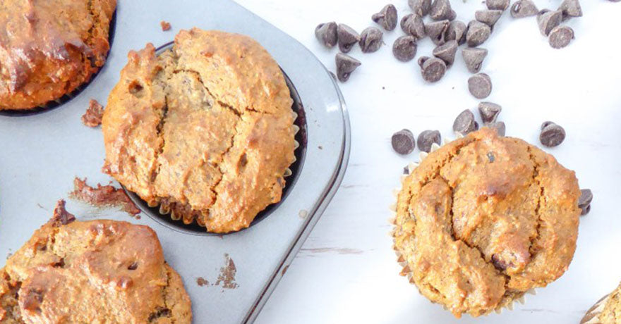 Muffins in a muffin pan, chocolate chips sprinkled 